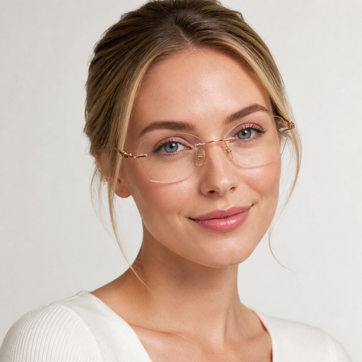 Gold rimless rectangular glasses worn by an attractive young adult White woman in a light studio