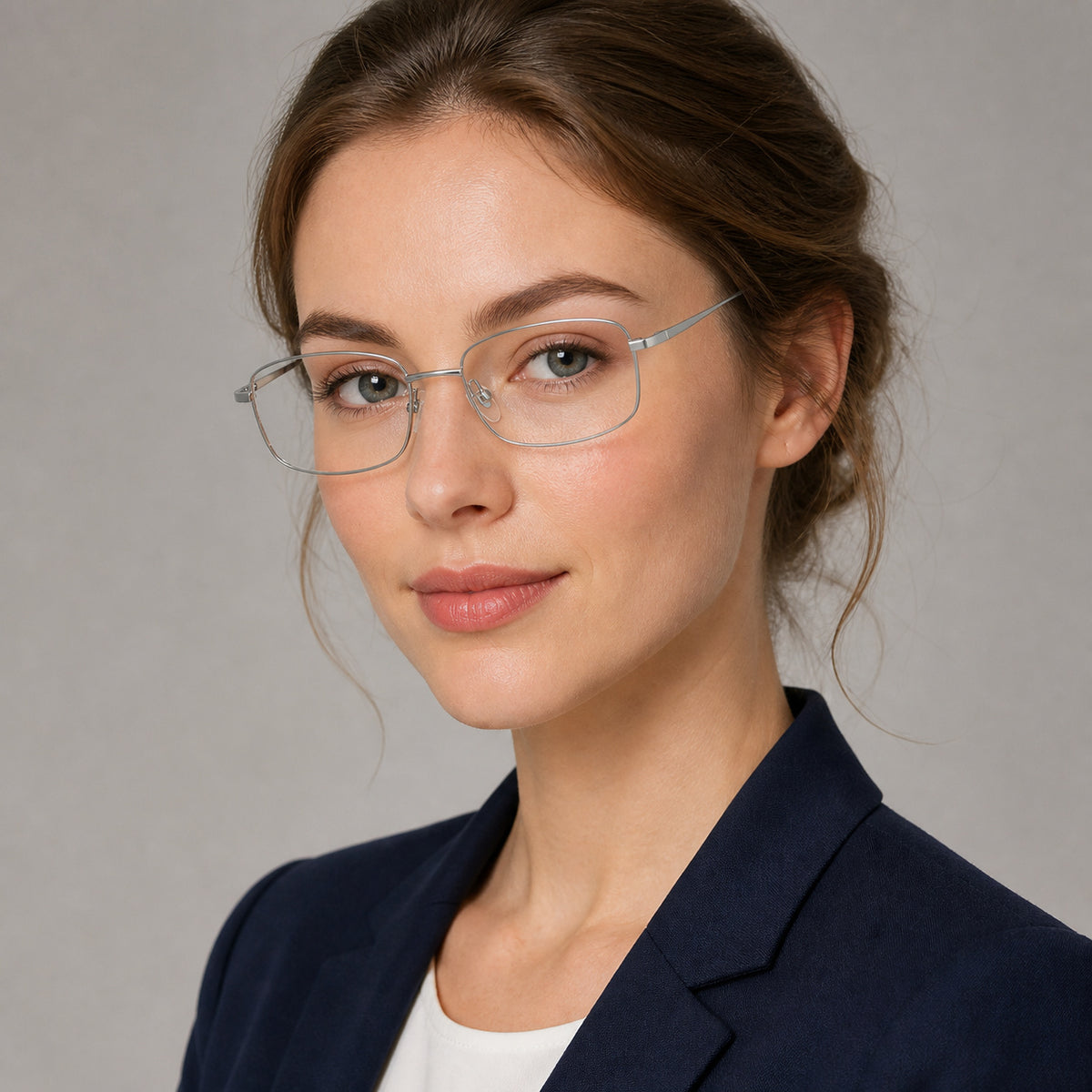 Silver narrow rectangular glasses worn by an attractive young adult White woman in a navy blazer